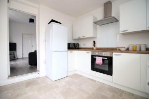 a kitchen with white cabinets and a stove top oven at Rugby Place by Tŷ SA in Newport