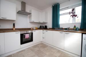 a kitchen with white cabinets and a stove top oven at Rugby Place by Tŷ SA in Newport