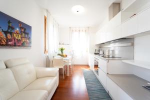 a living room with a white couch and a kitchen at Casa Elti - Shanti and Jay apartments in Venice-Lido
