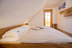 a bed with white sheets and pillows in a room at Cottage Osojnik - Alpine escape with Wellness in Solčava