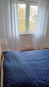 a bedroom with a blue bed and two windows at Apartamenty Bałtyk Park in Ustka