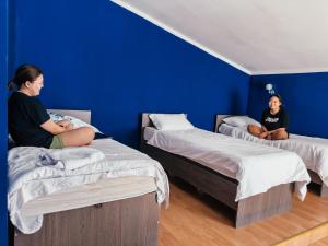 duas mulheres sentadas em camas num quarto com paredes azuis em Red Apple Hostel em Almaty