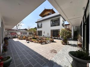 a large white house with a courtyard with potted plants at Lijiang Hengchang Baoyin Mohuakai Inn in Lijiang