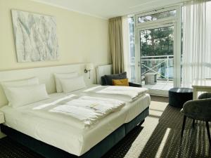 ein Schlafzimmer mit großem Bett und großem Fenster in der Unterkunft Strandhotel Fischland in Dierhagen