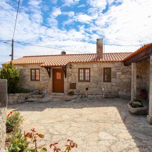 una pequeña casa de piedra con techo rojo en 2 bedrooms villa with city view enclosed garden and wifi at Sorthela, en Sortelha