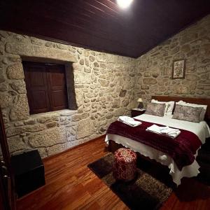 1 dormitorio con 1 cama en una pared de piedra en 2 bedrooms villa with city view enclosed garden and wifi at Sorthela, en Sortelha
