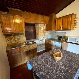 una cocina con armarios de madera y una mesa con una cesta. en 2 bedrooms villa with city view enclosed garden and wifi at Sorthela, en Sortelha