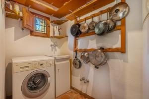 a laundry room with a washing machine and pots and pans at Casita de la Huerta in Granada