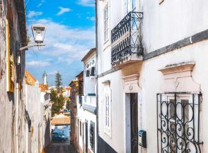 an alley with white buildings and a balcony at Kampaoh Tavira in Tavira