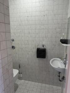 a white tiled bathroom with a sink and a shower at Ferienwohnung Kity mit Terrasse und Bergblick in Grainau +17 photos