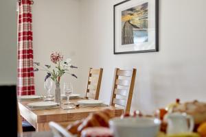 una mesa de madera con sillas y una mesa con gafas en Monmouth Retreat Cottage, en Beckington