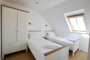 two beds in a white room with a window at Monmouth Retreat Cottage in Beckington