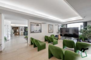 a living room with green chairs and a flat screen tv at HOTIDAY Hotel Giulianova in Giulianova