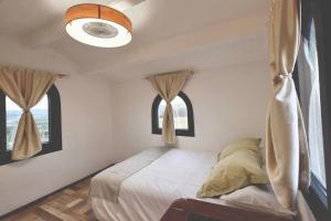 a bedroom with a bed and two windows at Torre Costa Brava in Garrigás