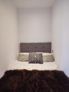 Una cama con una manta marrón y almohadas. en Bright and spacious studio flat en Londres