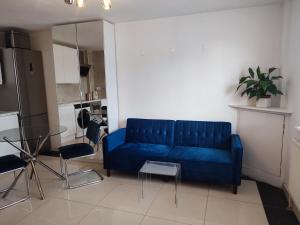 a living room with a blue couch and a table at Bright and spacious studio flat in London