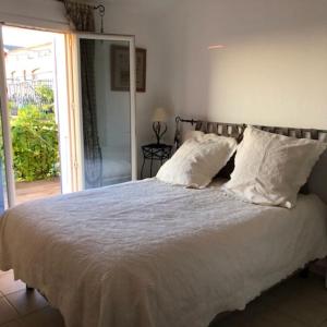 un lit avec des draps blancs et des oreillers dans une chambre dans l'établissement Villa la Provençale, à Roquebrune-sur Argens