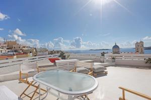 a patio with a glass table and chairs on a roof at San Nikolas view guest house in Ermoupoli