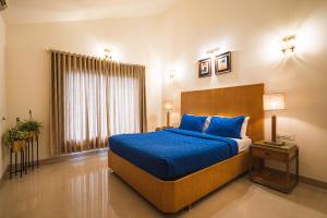 1 dormitorio con cama con sábanas azules y ventana en Villas By Hangout, en Lonavala