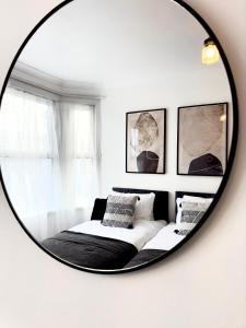 a mirror in a white room with a bed at Serviced 4 bed 2 bath Manor Park House in London