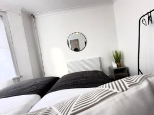 a bedroom with a black and white bed and a mirror at Serviced 4 bed 2 bath Manor Park House in London