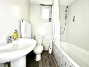 Baño blanco con lavabo y aseo en Serviced 4 bed 2 bath Manor Park House, en Londres