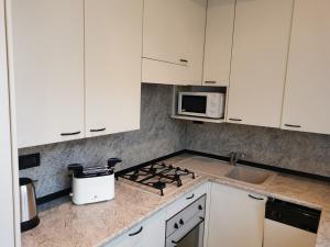 a kitchen with white cabinets and a stove top oven at casa di Ale e Bea in Dervio