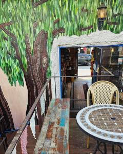 un tavolo con sedie e un muro con un murale sull'albero di Pedro's House - Foreigners only a Gwangju