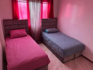 - 2 lits dans une chambre aux murs roses et aux fenêtres dans l'établissement Luxueux appartement à Sahara beach mohammedia, à Minaret de Mansuria
