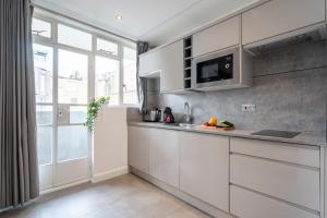 a kitchen with white cabinets and a large window at Stay at Whitfield Street in London