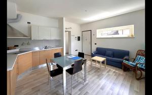 a kitchen and living room with a table and a blue couch at Gardenia Apartment Ossuccio in Ossuccio