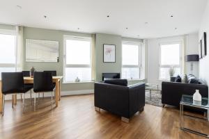 uma sala de estar com uma mesa, cadeiras e janelas em The Islington Apartments em Londres