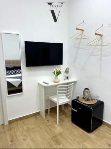 a white desk with a chair and a tv on a wall at Ventre luxury rooms in Naples