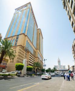 麥加的住宿－Manarat Gaza Hotel - Al Haram Tower，一座高大的建筑,前面有一辆汽车