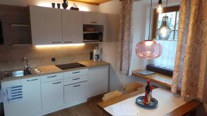 eine Küche mit weißen Schränken, einem Tisch und einem Fenster in der Unterkunft Haus Groder in Rauris