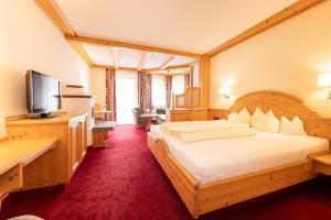 ein Hotelzimmer mit einem großen Bett und einem Flachbild-TV in der Unterkunft Aktiv & Vitalhotel Bergcristall in Neustift im Stubaital