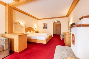 1 dormitorio con 1 cama grande y alfombra roja en Aktiv & Vitalhotel Bergcristall, en Neustift im Stubaital
