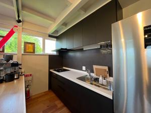 a kitchen with black cabinets and a stainless steel refrigerator at Straddie House Niseko in Niseko