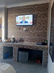 TV en una pared de ladrillo con chimenea en Orchard Mist Lodges and Events en Kabwe