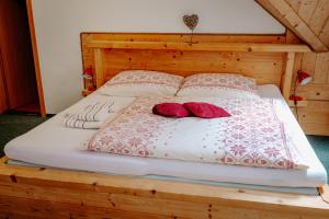 Una cama con dos almohadas rojas encima. en Penzión Sova Ždiar, en Ždiar