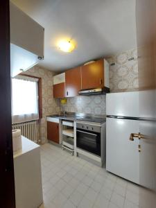 a kitchen with a white refrigerator and a stove at Quadrilocale Alberti - Residence dei Fiori in Madonna di Campiglio