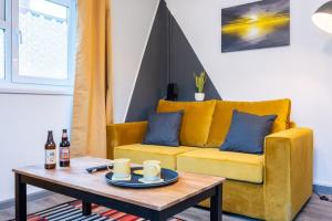 a living room with a yellow couch and a coffee table at Free Parking - The Coach House B by Tŷ SA in Cardiff
