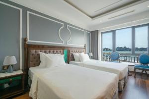 ein Hotelzimmer mit 2 Betten und einem Balkon in der Unterkunft Charmhill Hotel - Tuần Châu in Hạ Long