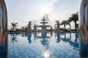 a large swimming pool with a fountain in the background at Charmhill Hotel - Tuần Châu in Ha Long