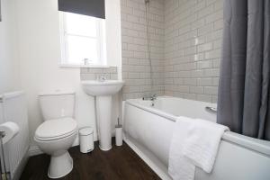 a white bathroom with a toilet and a tub and a sink at Gwent View by Tŷ SA in Newport