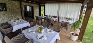 een restaurant met tafels en stoelen met witte tafelkleden bij Plitvice Inn in Jezerce