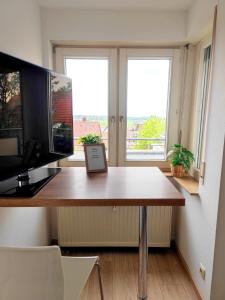 a room with a desk with a television and two windows at Stilvolles Studio nahe Messe und Airport in Leinfelden-Echterdingen