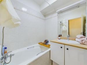 een badkamer met een bad, een wastafel en een spiegel bij Cozy Studio vue Parc in Rueil-Malmaison