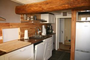 cocina con armarios blancos y pared de madera en Eulennest, en Lauterbach