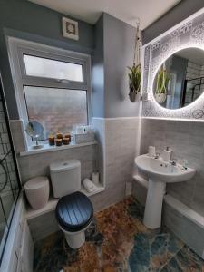 y baño con aseo, lavabo y espejo. en Junctions Way by Tŷ SA -3 bed in Newport en Newport